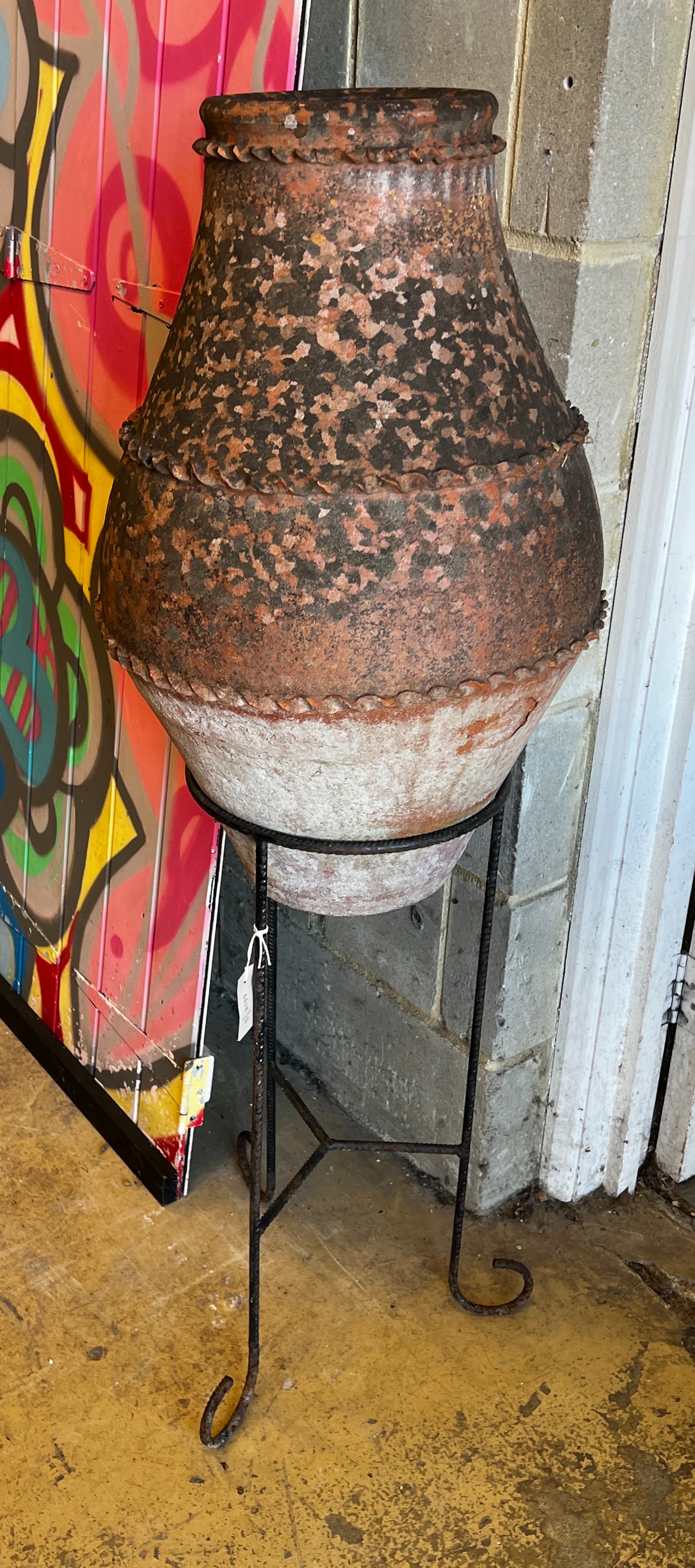 A glazed terracotta urn on wrought iron stand, height 130cm